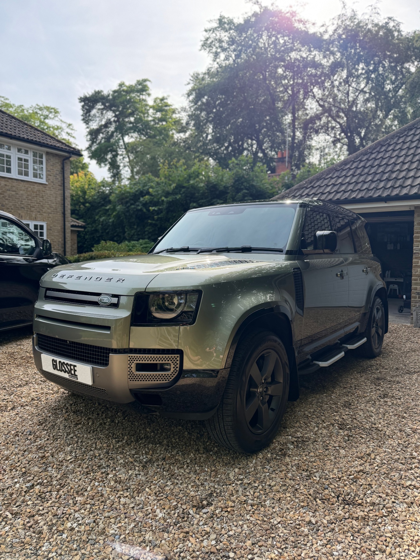 Satin green Land Rover Defender parked on gravel driveway