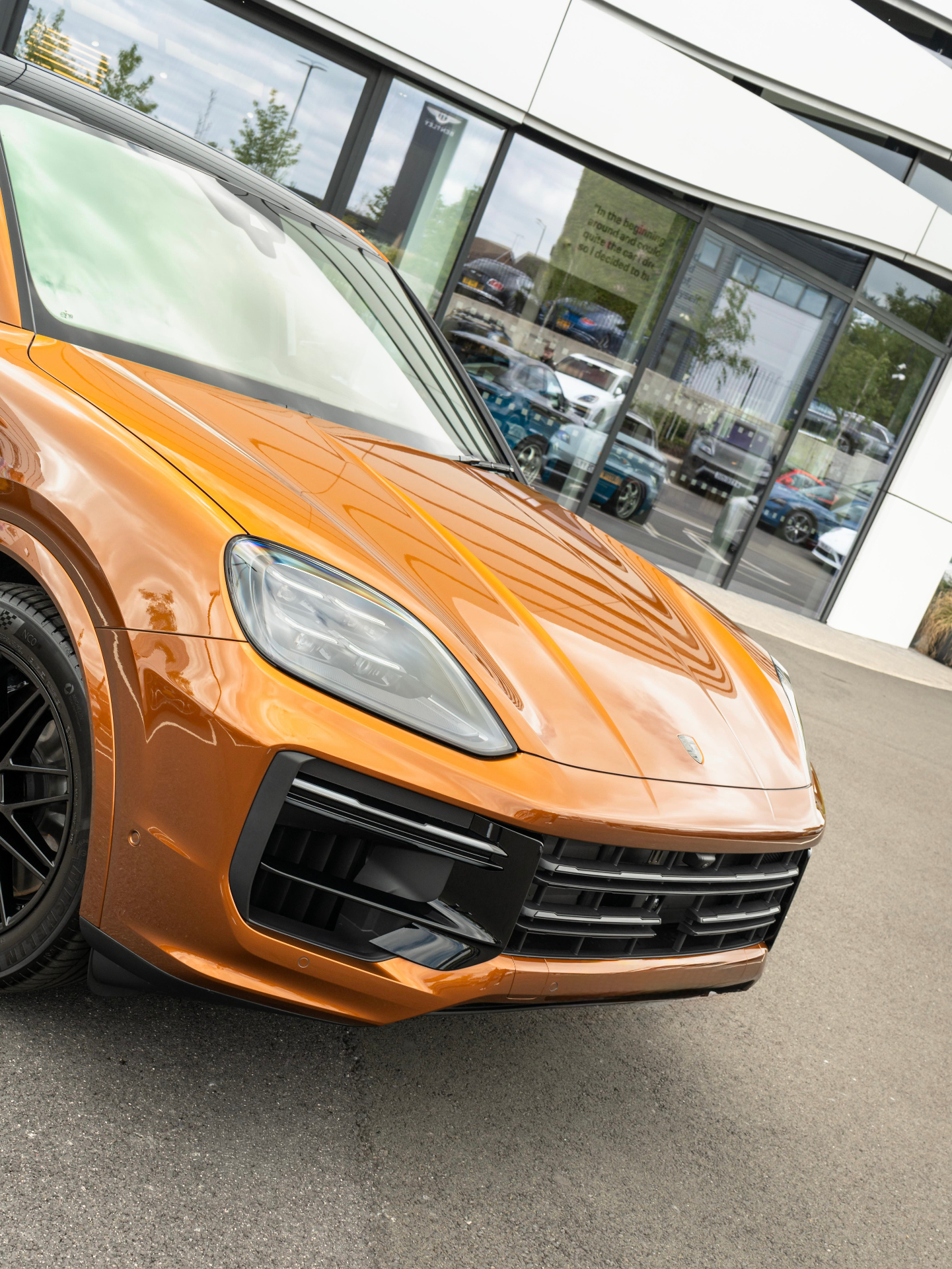 Orange Porsche Cayenne front detail outside showroom