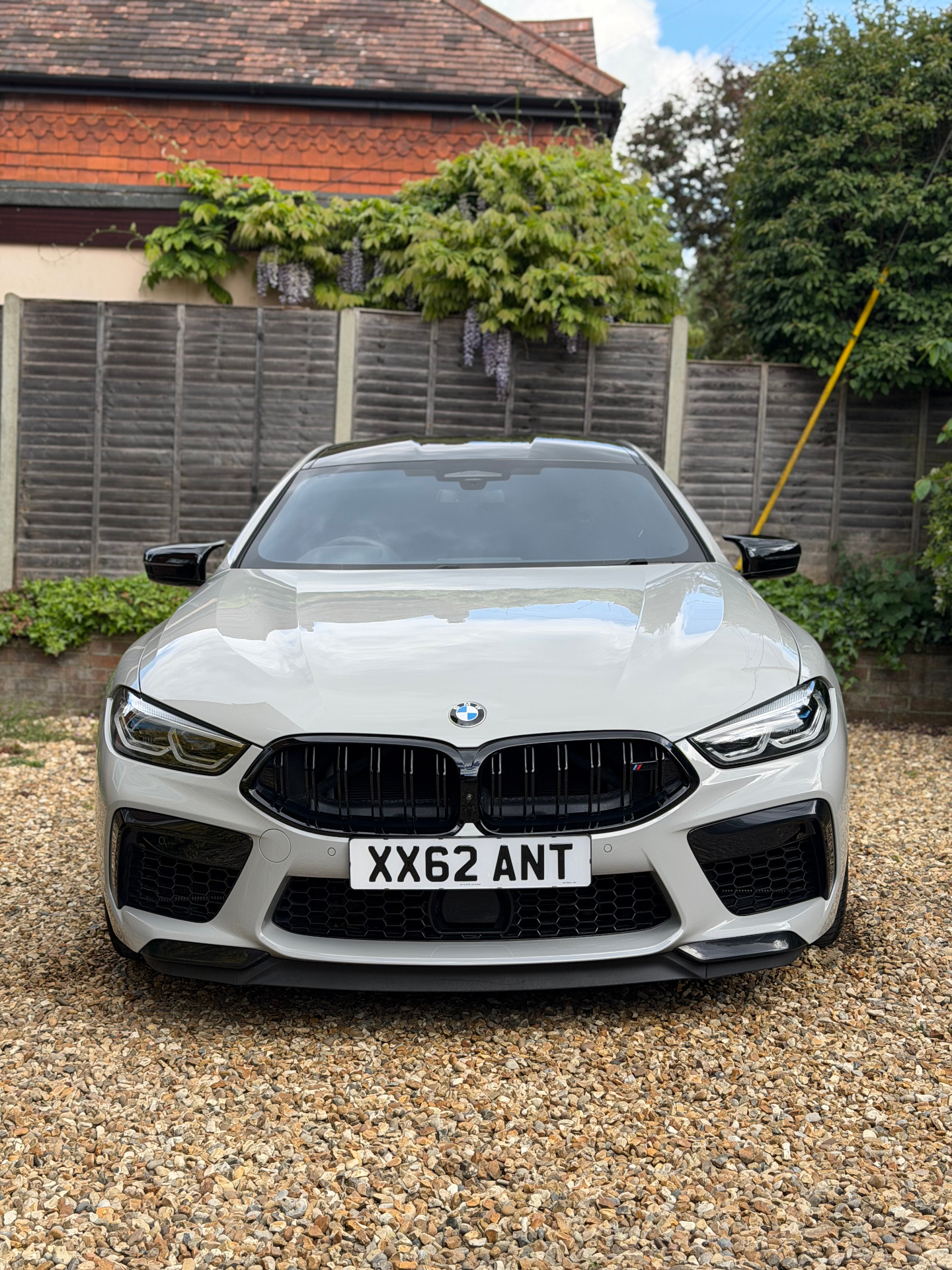 White BMW M8 front view on gravel driveway